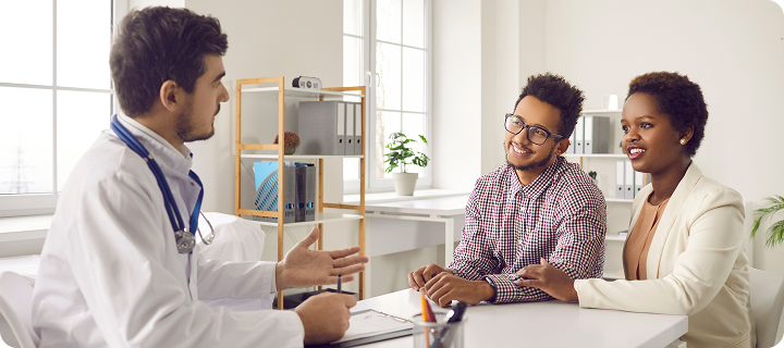Doctor explaining insurance costs to a couple, showing how health coverage premiums and deductibles work together