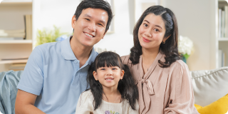 Family of three smiling at home, representing health coverage access under the Affordable Care Act