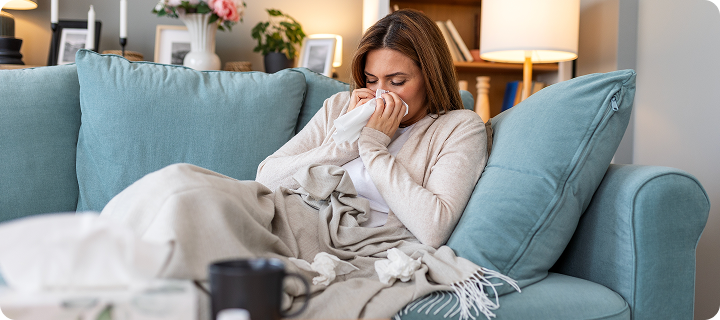 Cold And Flu. Portrait Of Ill Woman Caught Cold, Feeling Sick And Sneezing In Paper Wipe. Closeup Of Beautiful Unhealthy Girl Covered In Blanket Wiping Nose. Healthcare Concept.