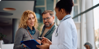 Mid adult woman with husband talking to a doctor about their medical test results at the clinic.