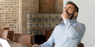 Tired Hispanic Man Working Remotely from Office experiencing afternoon slump
