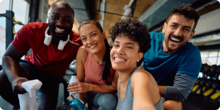 Multiracial group of happy athlete taking selfie in a gym and looking at camera. Focus is on African American woman.
