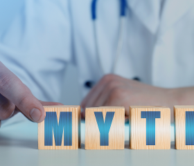 Doctor arranging wooden blocks spelling "MYTHS," representing common medical myths and healthcare misinformation.