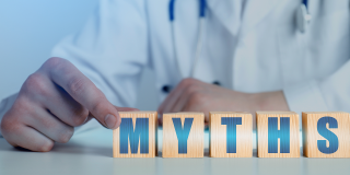 Doctor arranging wooden blocks spelling "MYTHS," representing common medical myths and healthcare misinformation.