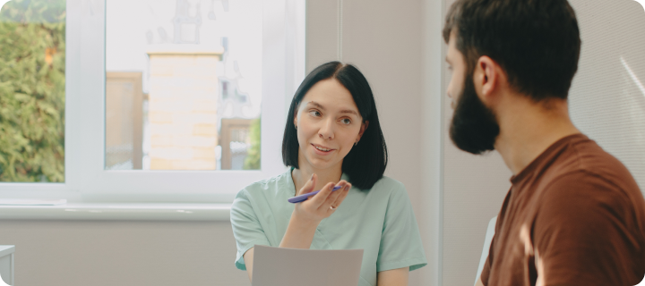 Young adult discussing personal healthcare needs and available support with a medical professional during an in-person consultation.