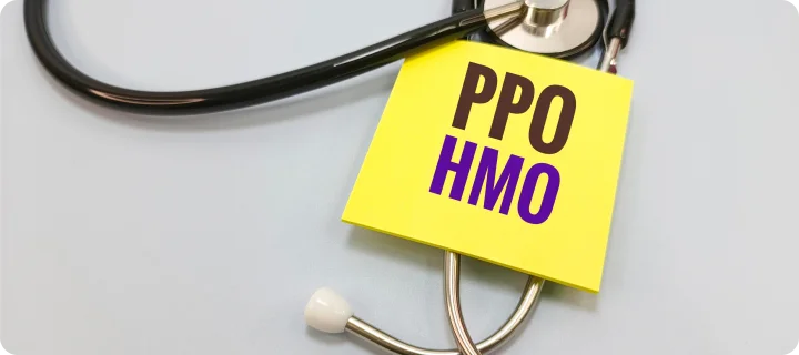 Stethoscope surrounding a note labeled "PPO HMO," illustrating the comparison between PPO and HMO health insurance plans and healthcare coverage options.