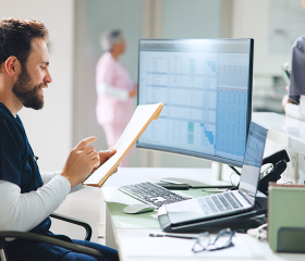 Healthcare professional reviewing patient information on a computer at a medical office.