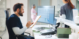 Healthcare professional reviewing patient information on a computer at a medical office.