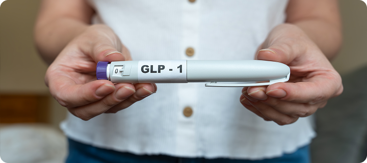 Person holding a GLP-1 injection pen, representing GLP-1 medication and insurance coverage.