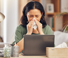 Woman with cold symptoms working from home, highlighting Coverage Fox during cold and flu season.
