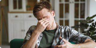 Stressed man checks his device at home, highlighting how wearable tech for better health can support daily wellness.