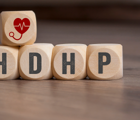 Wooden blocks spelling “HDHP” with a heart and stethoscope icon representing a high-deductible health plan.
